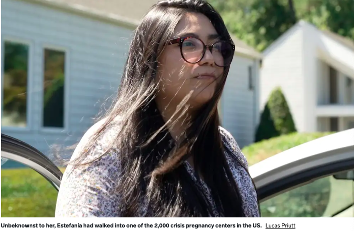 A young woman with glasses stares ahead.